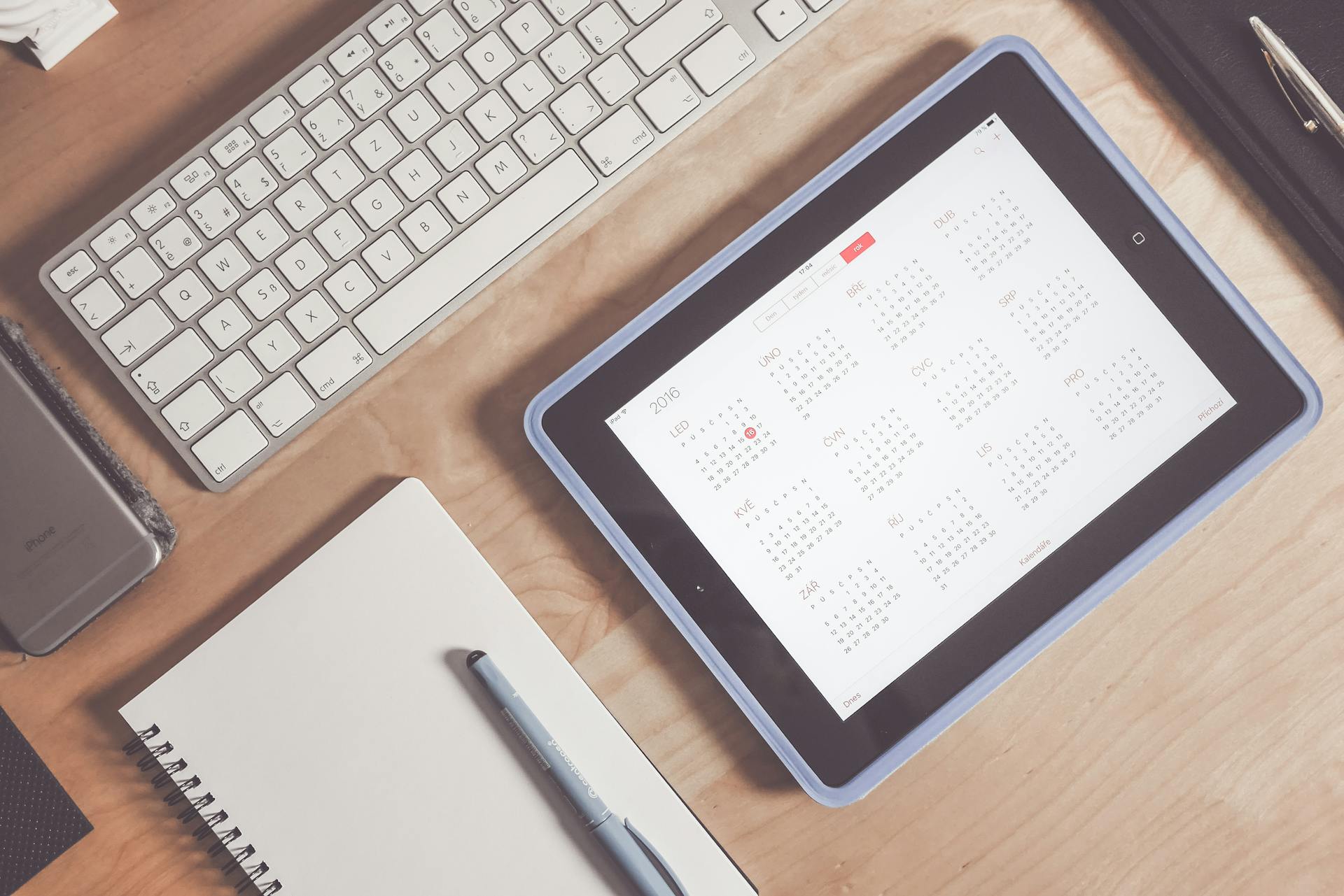 A desk setup with an iPad showing a calendar, a keyboard, and a notebook, symbolizing content planning for a food blog in 2026.