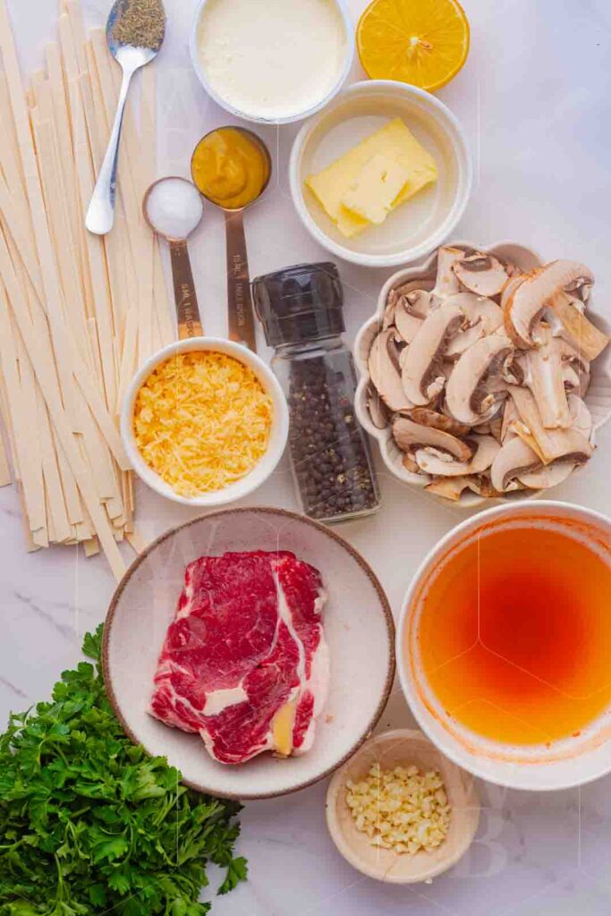 Food photography tips example: overhead ingredient shot with raw steak, pasta, mushrooms, butter, and stock laid out in small bowls
