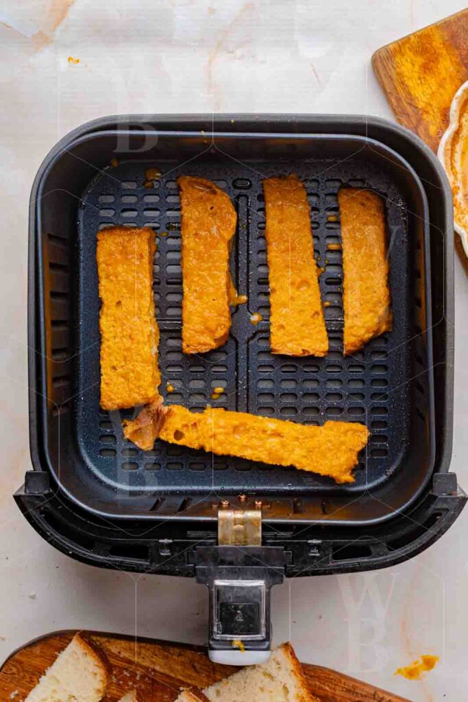 Overhead view of French toast sticks cooking in an air fryer basket