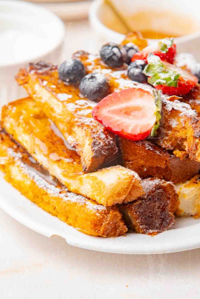 Close-up of French toast sticks stacked with strawberries and blueberries