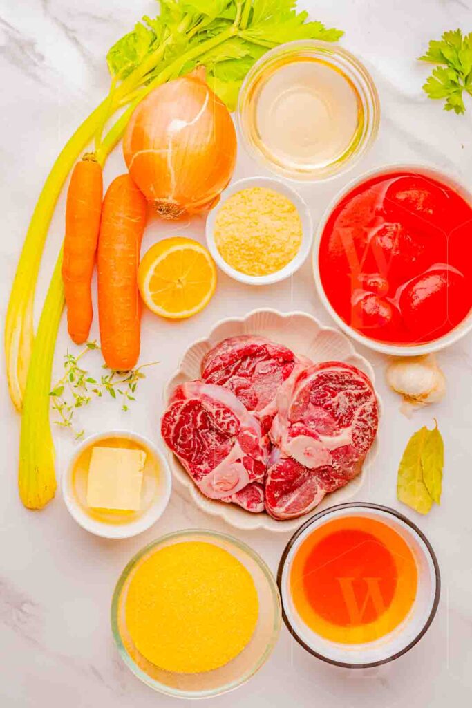 Overhead ingredient shot with raw ossobuco, vegetables, and seasonings laid out in small bowls