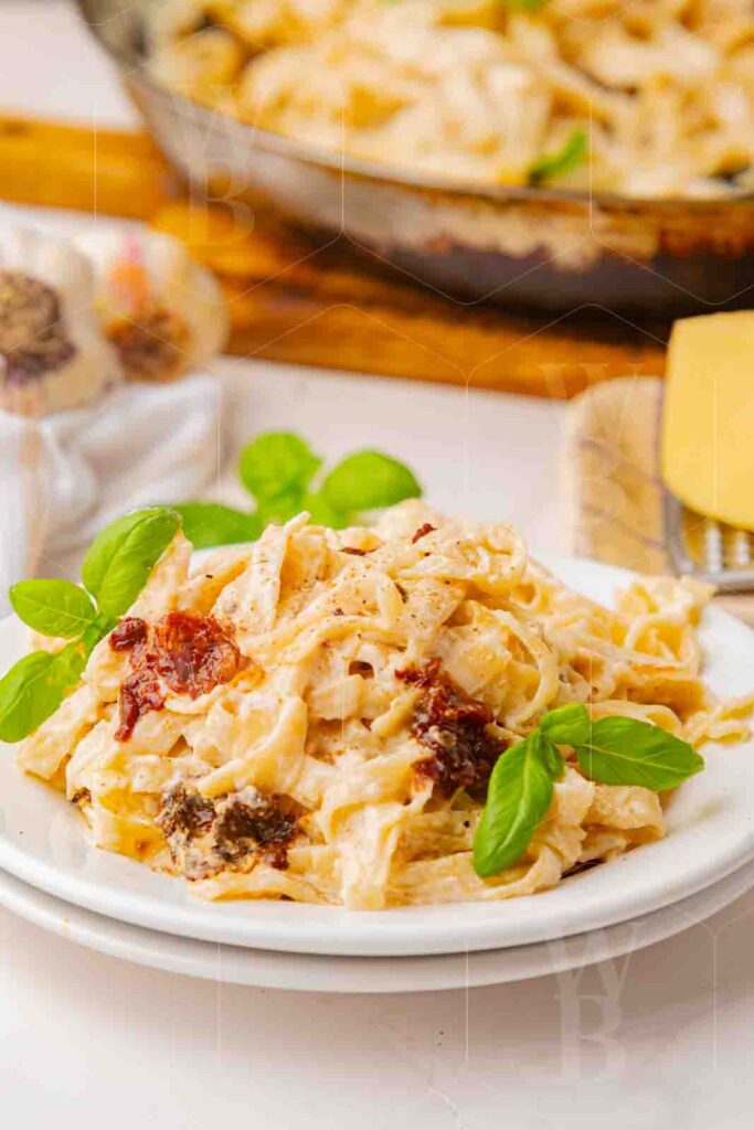 45 degree hero shot of creamy fettuccine with fresh basil on a white plate